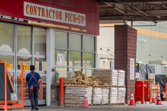 Calgary, Alberta, Canada. September 27, 2026. A store employee walking near a contractor pick-up loading zone with stacked cement bags.