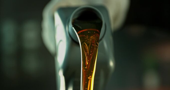 Super slow motion (1000 fps) close-up of motor oil pouring from a container. Smooth golden liquid flow with bubbles and reflections, isolated cinematic shot with shallow depth of field. Speed ramp eff