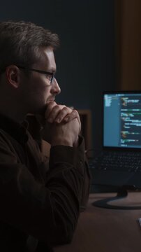 Smiling coder excited about AI-assisted programming at his home office workstation with artificial intelligence agent writing programming code, and working on project itself on computer screen.