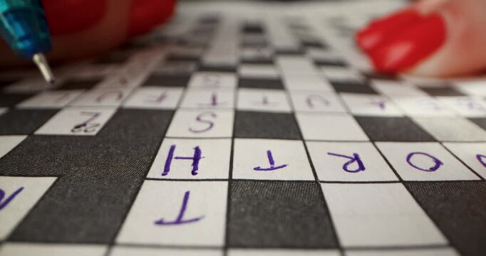 Brain training games. Hand writing answer in crossword puzzle. closeup