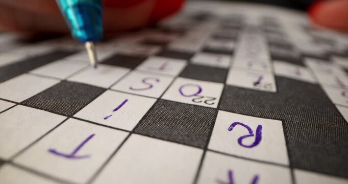 Brain training games. Hand writing answer in crossword puzzle. closeup