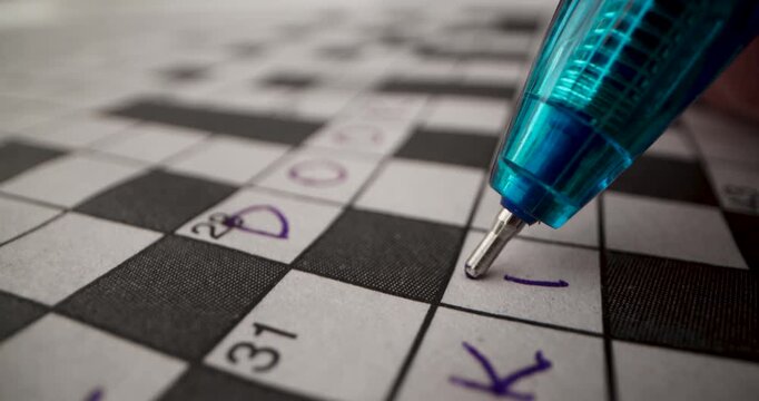 Brain training games. Hand writing answer in crossword puzzle. closeup
