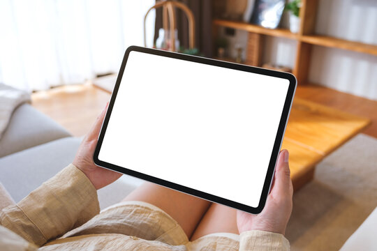 Mockup image of a woman holding tablet with blank desktop white screen at home