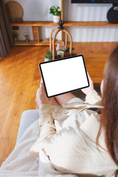 Top view mockup image of a woman holding tablet with blank desktop white screen at home