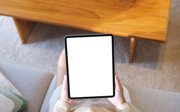 Top view mockup image of a woman holding tablet with blank desktop white screen at home