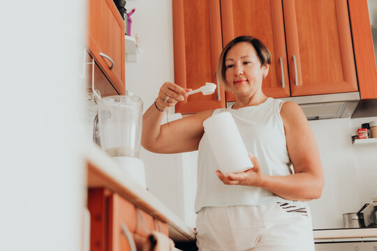 Woman preparing psyllium husk fiber supplement in kitchen for gut health digestive health microbiome support soluble fiber high fiber diet gluten free baking wellness nutrition and functional food
