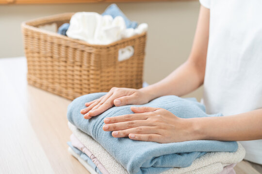 Feel softness, chore of asian young woman, girl housewife hand holding pile clothing from table, stack folding clean clothes after washing, laundry and dry, working at home. Laundry maid in household.