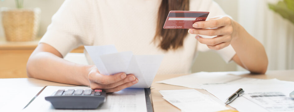 Financial owe, stressed asian woman, girl hand holding credit card, stressed by calculate expense from invoice or bill, no money to pay, mortgage or loan on table at home. Debt, bankruptcy or bankrupt