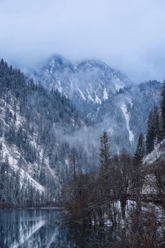 Winter landscape of Jiuzhaigou Valley, snowy mountains and partly frozen lake with pine forest in Sichuan, China