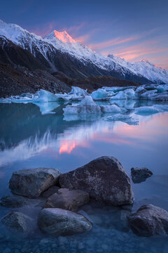 Golden dawn reflecting across Tasman Lake with Aoraki Mount Cook rising above the Southern Alps, New Zealand