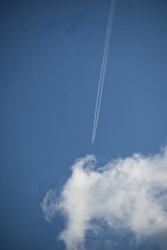 Passenger airplane leaving contrails in a blue sky above white clouds