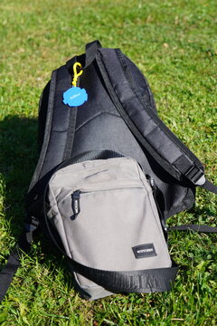 A black backpack and a grey Wittchen shoulder bag resting on a lush green grass lawn outdoors
