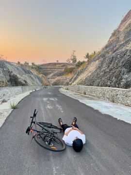 Cyclist Resting on Road Surrounded by Hills