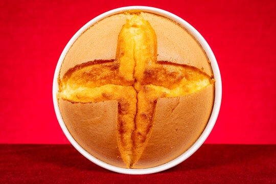 Round sponge cake with cross crack in white baking bowl