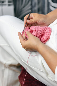 Woman crochets bag made of knitted pink threads. Engaging hobby