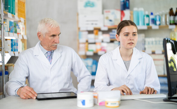 Male and female pharmacists working with computer and tablet in chemist's shop