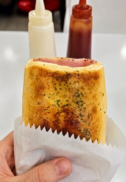 Crispy Grilled Ham and Cheese Sandwich Held by Hand with Condiments in Background