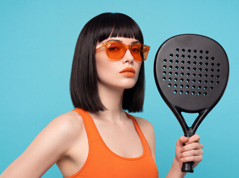Stylish female athlete posing with a modern sport racket in a professional studio setup