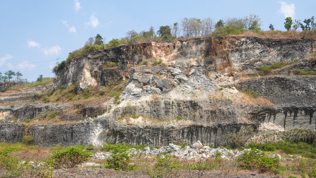 Former limestone quarry site in Sukolilo, Pati, Central Java, Indonesia. Rugged cliff face of open-pit mine showing excavated white stone layers for cement and construction material production.