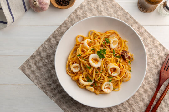 Stir fried linguine pasta with squid and chilli ,garlic with olive oil in white plate.Octopus Spaghetti Aglio e Olio.Top view.