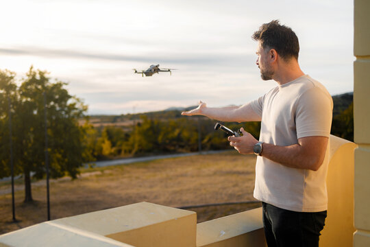 Man controls drone at sunset over open field
