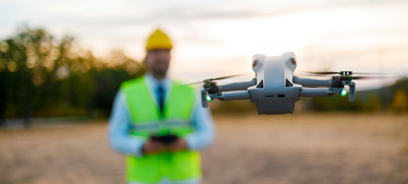 Drone operates at a construction site during sunset with a worker present