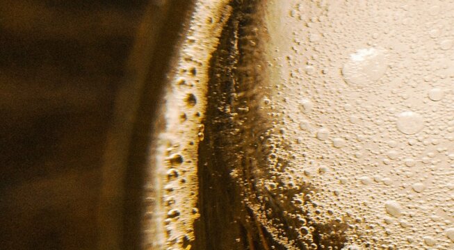 Macro close up of cold golden beer foam and bubbles