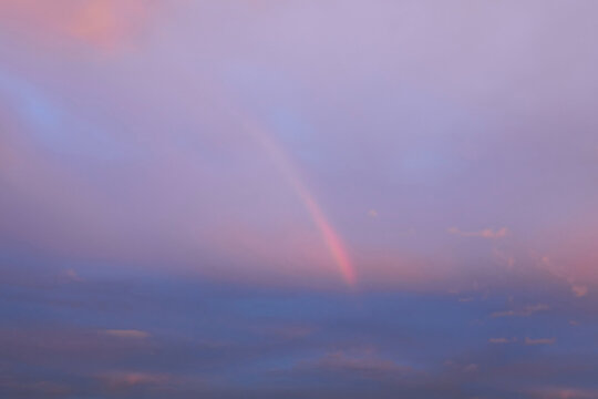 the end of a rainbow peaking through the pinkish clouds right before a rainstorm, with copy space