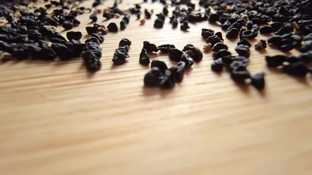 Macro close-up video of organic leek seeds scattered across a wooden surface, highlighting agricultural harvesting, gardening concepts, and healthy plant-based ingredients in a natural setting.   
