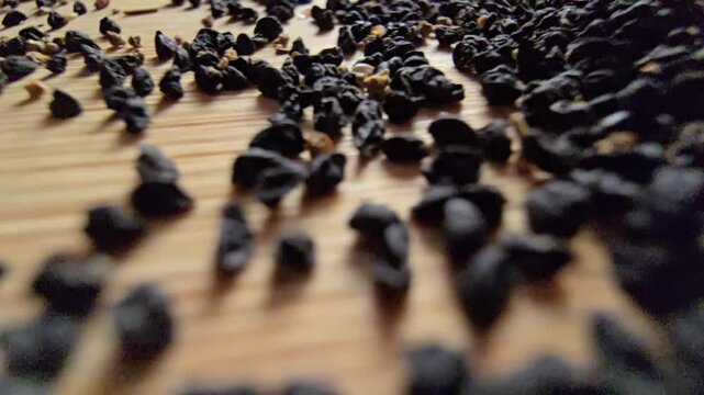 Macro close-up video of organic leek seeds scattered across a wooden surface, highlighting agricultural harvesting, gardening concepts, and healthy plant-based ingredients in a natural setting.   