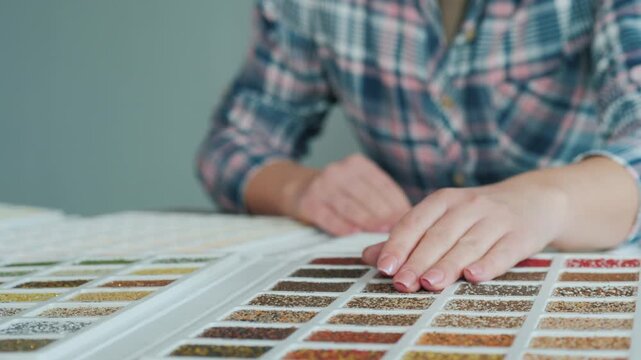 Woman artist chooses colored granules for diamond embroidery, needlework and creativity at the table, close up.