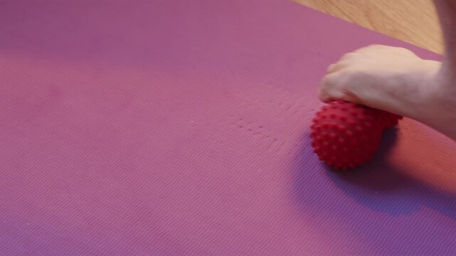 Person performing foot reflexology and fascia release with massage ball