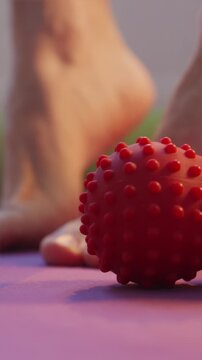 Red massage ball close up with foot stretching in background