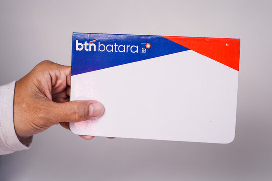 Makassar, Indonesia, September 20, A person's hand holding a BTN Batara iB sharia savings book against a plain light gray background.