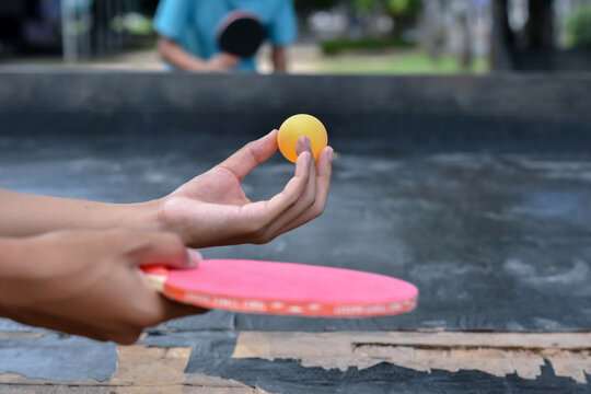 A player focuses on serving a yellow ball during a casual table tennis match.