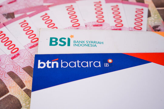 Makassar, Indonesia, September 20, Two Indonesian sharia bank passbooks, featuring BTN Batara iB and Bank Syariah Indonesia, arranged over a background of Indonesian 100.000 rupiah banknotes.