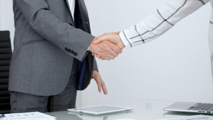 Business partners engaging in a handshake over an office desk with digital devices. Representing successful negotiation. Professional collaboration. Mutual trust © Hanna