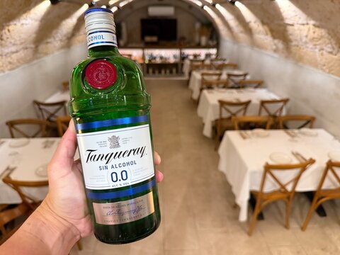 Mallorca, spain, septiembre 18, 2026 hand holding tanqueray 0.0 percent alcohol free gin bottle, offering a healthy alternative for responsible drinking in a restaurant