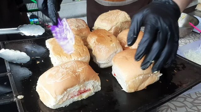 Chef spreading butter on buns on flat top grill
