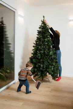 A woman and her son are making a Christmas tree at home