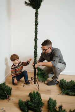A dad and his son are making a Christmas tree at home