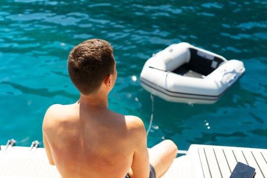 Man Sitting at Stern Before Swimming