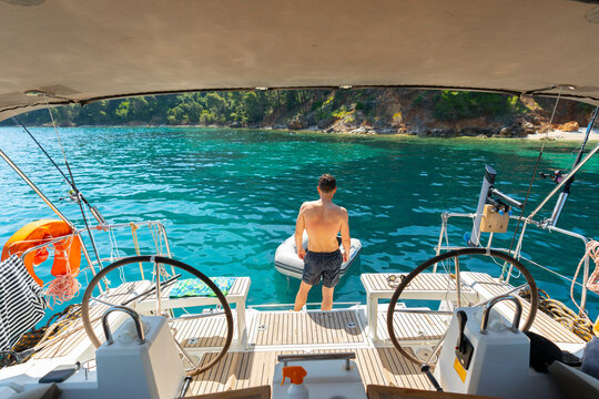 Man Standing at Stern of Sailing Yacht