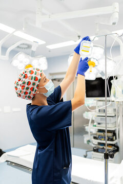 Female medical professional hanging iv drip in operating room