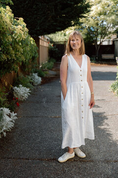 Smiling woman in white dress standing in sunny garden portrait