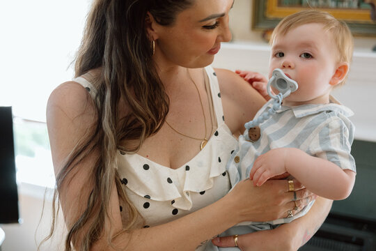 Mother holding baby with pacifier, tender candid moment