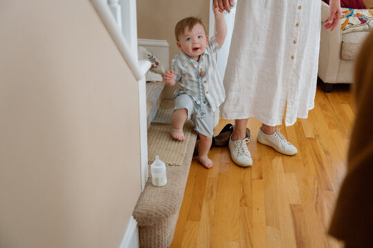 Candid toddler learning to walk on stairs holding parent's hand