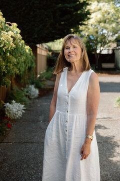 Candid outdoor portrait of a smiling mature woman in white dress