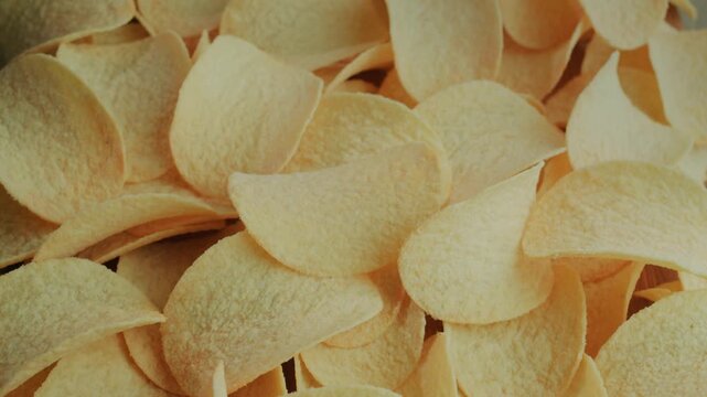 Crispy golden potato chips rotating slowly on a flat surface in cinematic close up view.