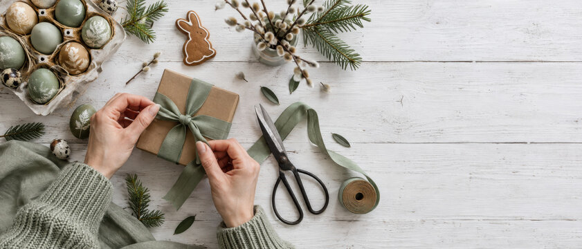 Sustainable gift wrapping with natural material, evergreen branch, handmade ornament and rustic craft on white wooden surface